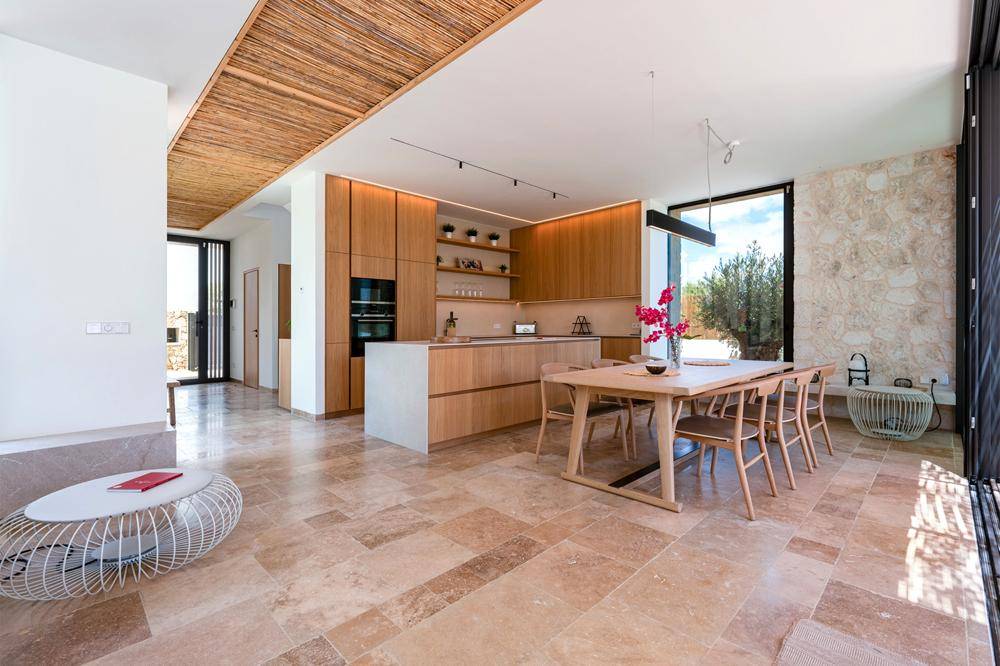 Moderne offene Küche mit Holzelementen, Essbereich und Zugang zur Terrasse.