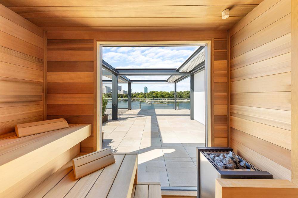 Holzvertäfelte Sauna mit Blick auf die Dachterrasse und die Stadt.