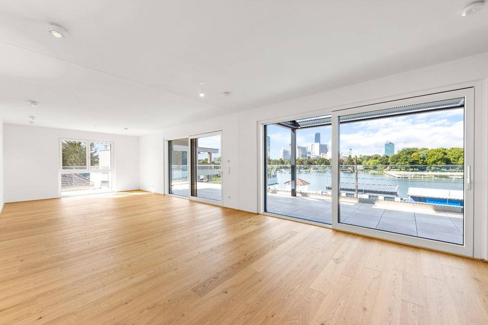 Geräumiges Wohnzimmer mit Holzboden und großen Schiebetüren zur Terrasse mit Stadtblick.