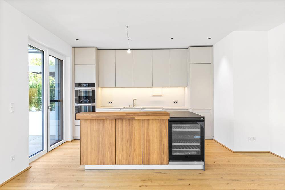 Moderne Küche mit heller Holzinsel, integriertem Weinkühler und Zugang zur Terrasse.