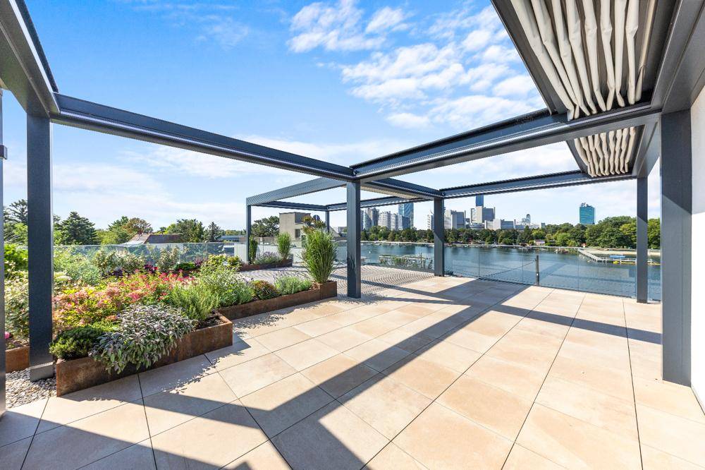 Großzügige Dachterrasse mit Fliesenboden, Pflanzenbeeten und weitem Blick über die Stadt.