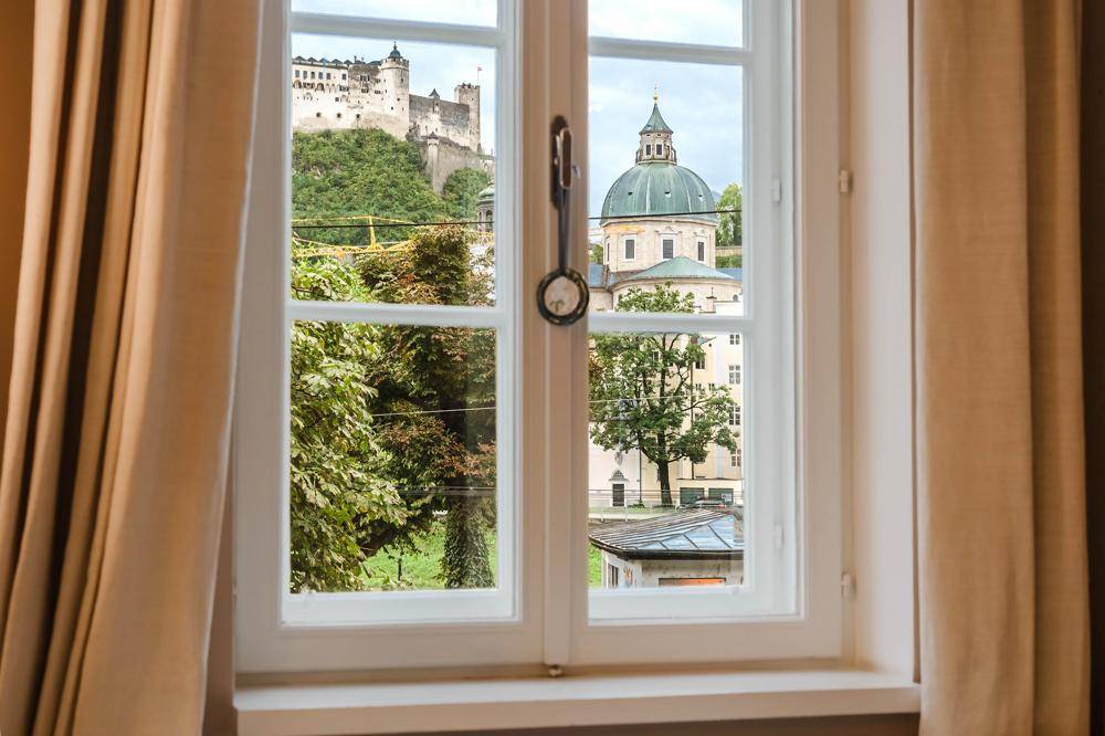 Fensterblick auf die Festung Hohensalzburg und die historische Altstadt von Salzburg.