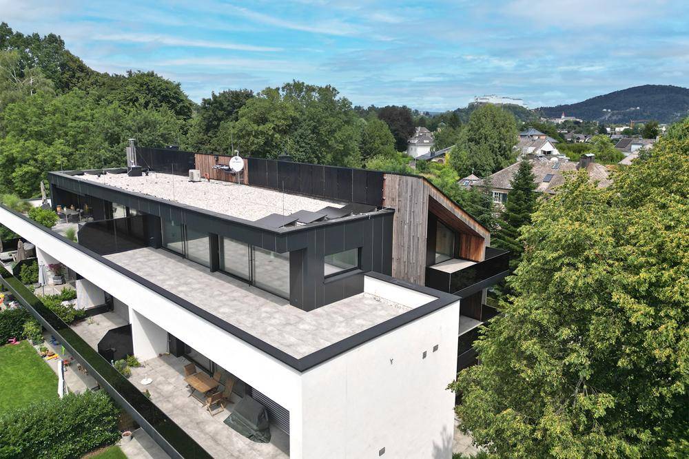 Moderne Architektur mit Flachdach, großen Terrassen und viel Grün in der Umgebung.