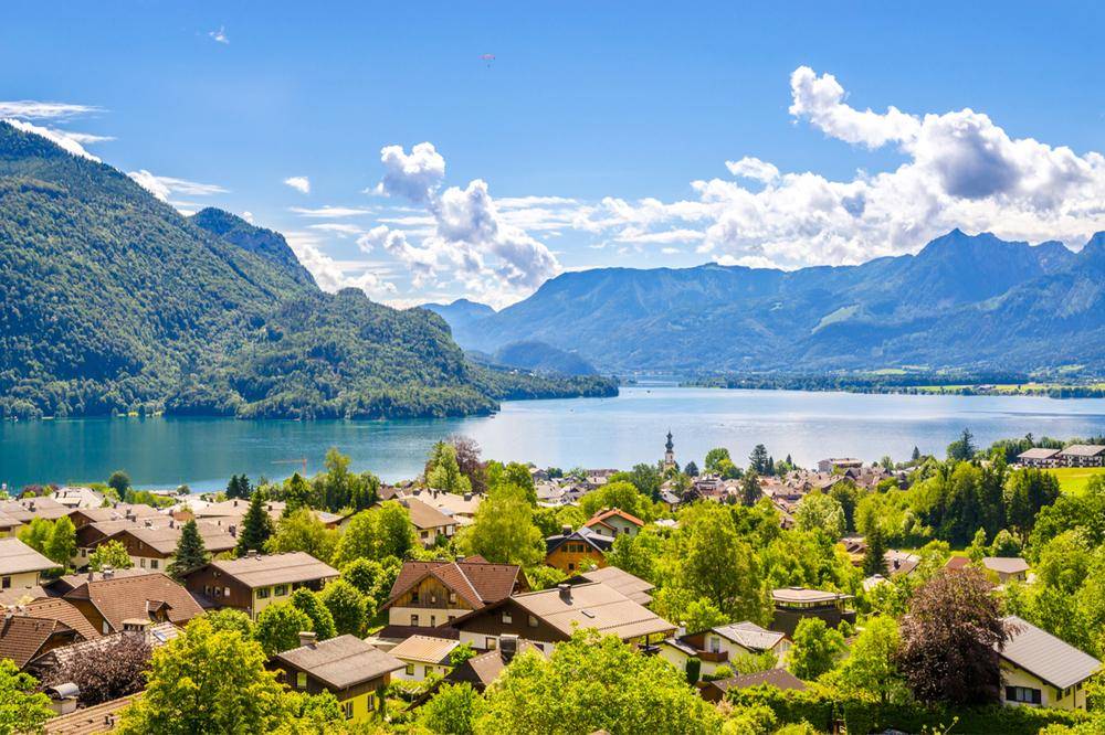 Panoramablick auf einen malerischen See, umgeben von Bergen und einem charmanten Dorf.