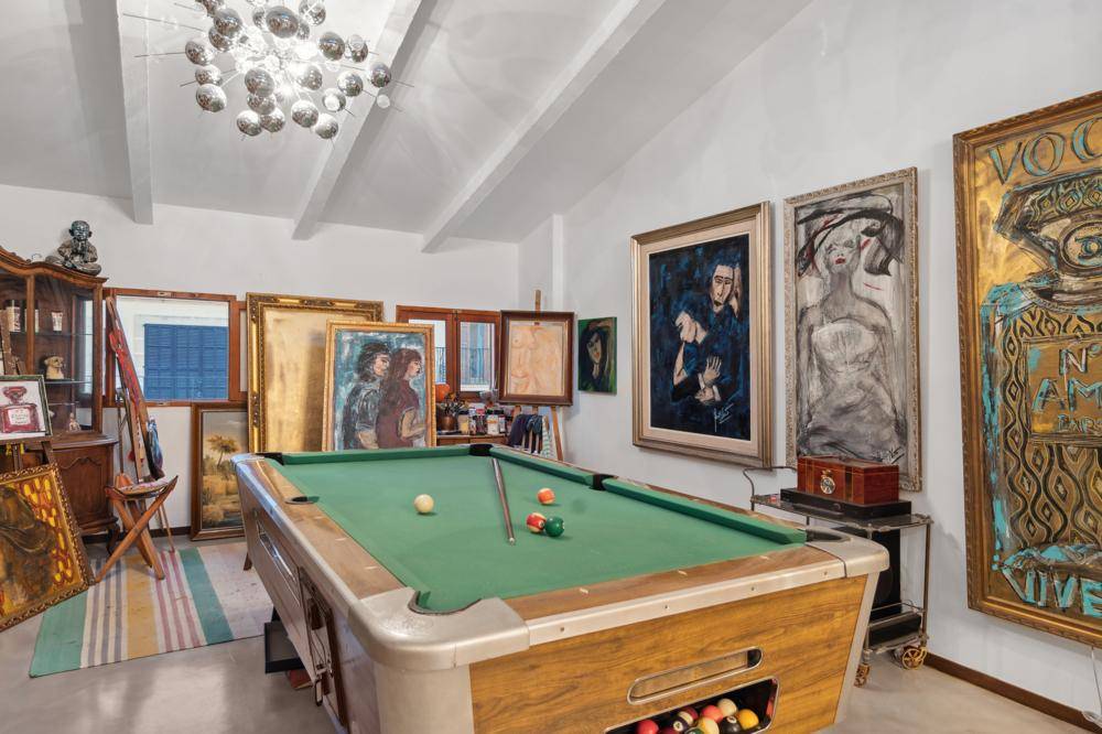 Geräumiger Spielraum mit Billardtisch, hohen Decken und zahlreichen Kunstwerken an den Wänden.