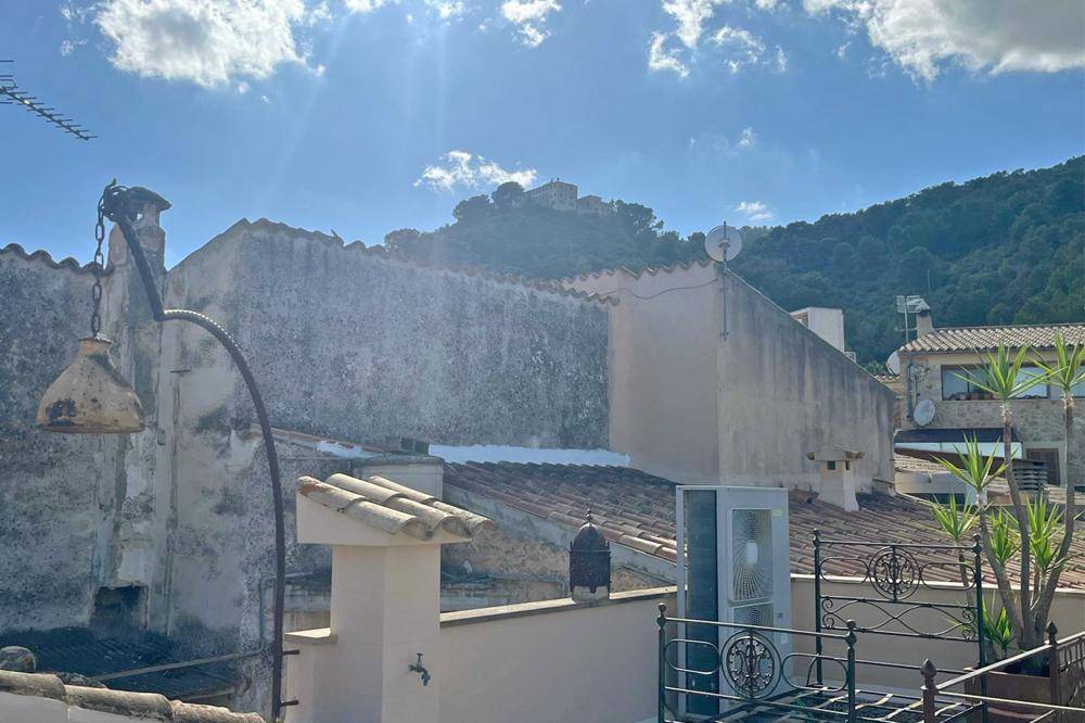 Blick von einer Dachterrasse über die Dächer der Nachbarschaft mit einem Hügel im Hintergrund.