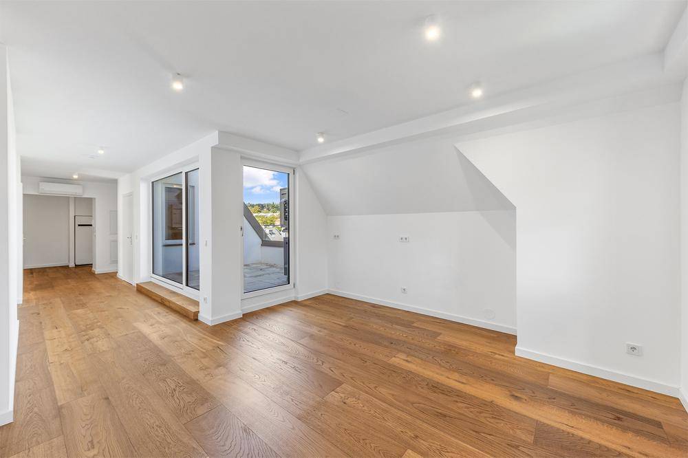 Geräumiges, helles Zimmer mit Holzboden, Schrägdach und großem Terrassenzugang.