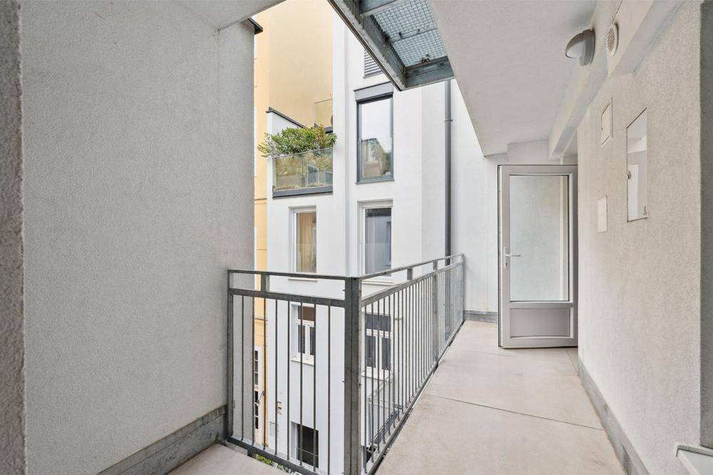 Schmaler Balkon mit Metallgeländer und Blick auf den Innenhof des Gebäudes.