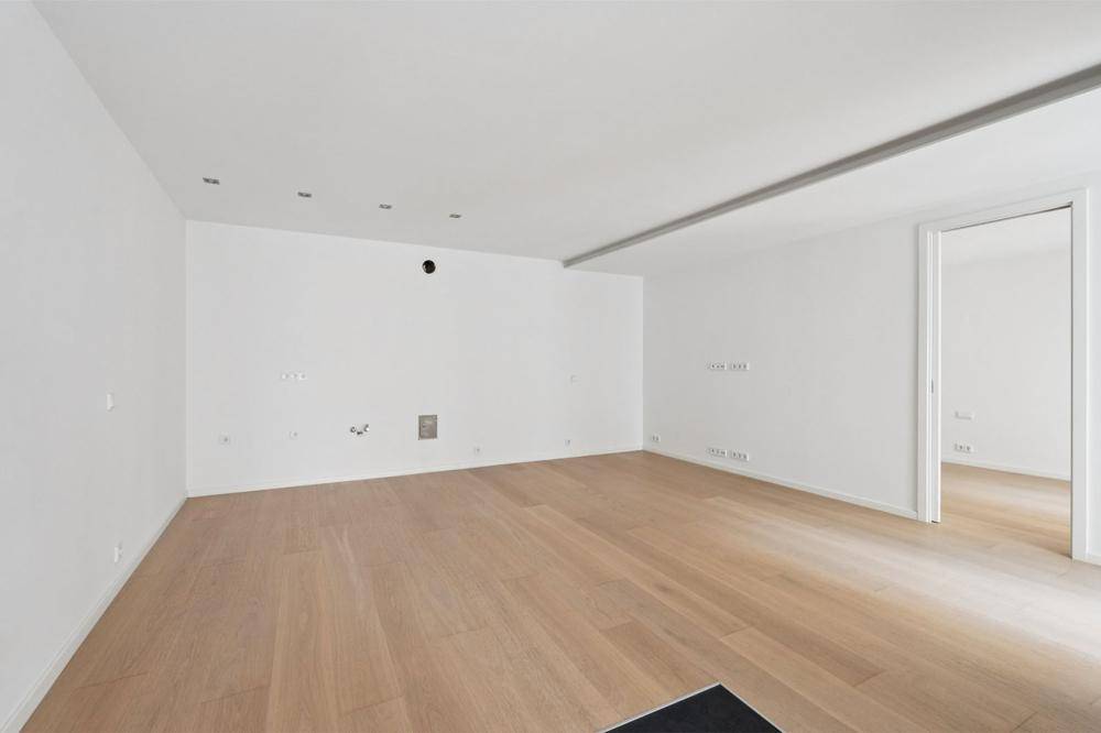 Geräumiger, heller Wohnraum mit Parkettboden und moderner Beleuchtung an der Decke.