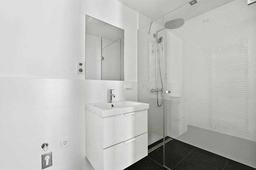 Modernes Badezimmer mit ebenerdiger Dusche, Einzelwaschbecken und beheiztem Handtuchhalter.