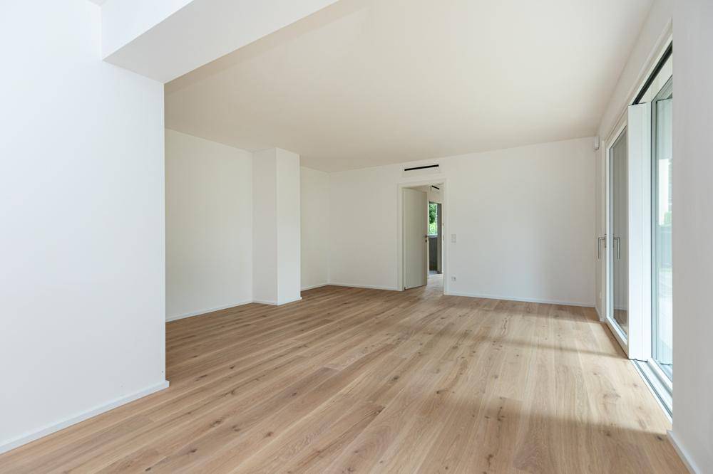 Geräumiger, heller Wohnbereich mit Holzboden und Zugang zu weiteren Räumen.