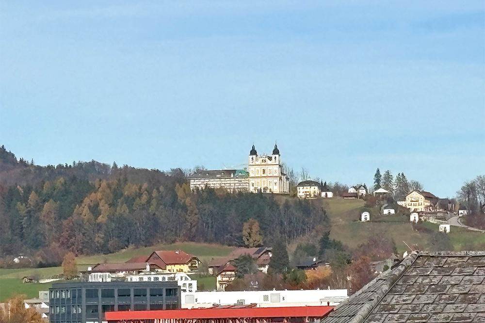 Malerischer Blick auf eine Kirche auf einem Hügel, umgeben von Bäumen und Häusern.