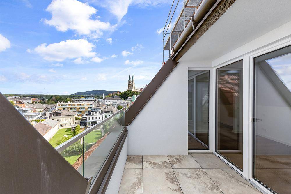 Geräumiger Balkon mit Fliesenboden und Glasbrüstung, bietet einen Panoramablick über die Stadt.