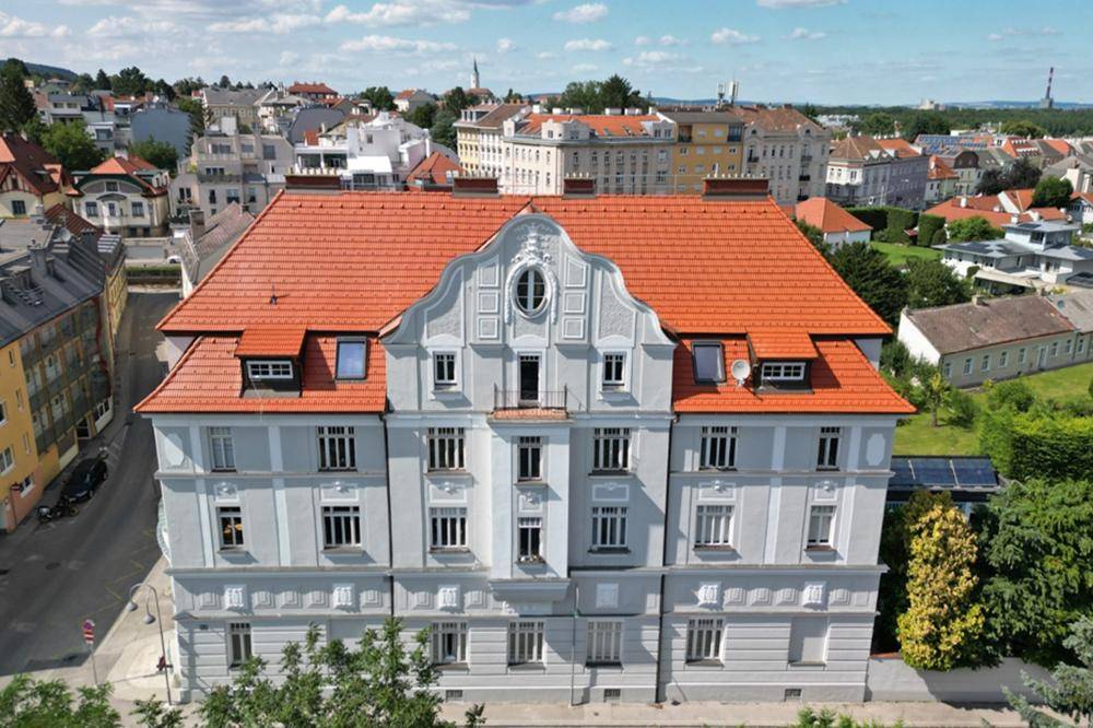 Historisches Gebäude mit markanter roter Dachlandschaft und detailreicher Fassade in städtischer Umgebung.