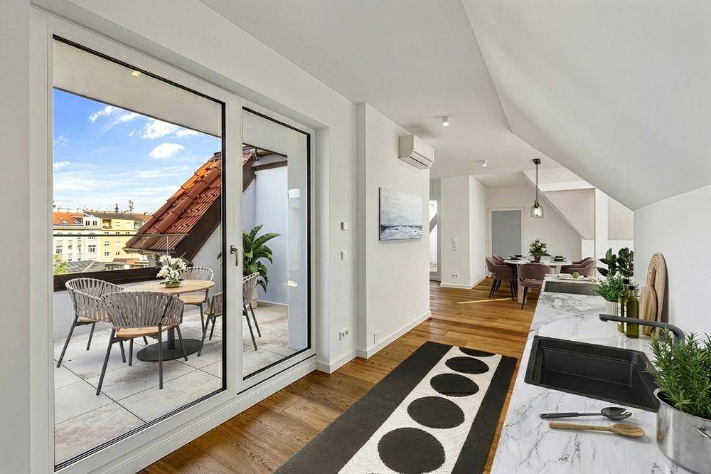 Moderne Küche mit Marmorarbeitsplatte und Zugang zu einem möblierten Balkon mit Stadtblick.
