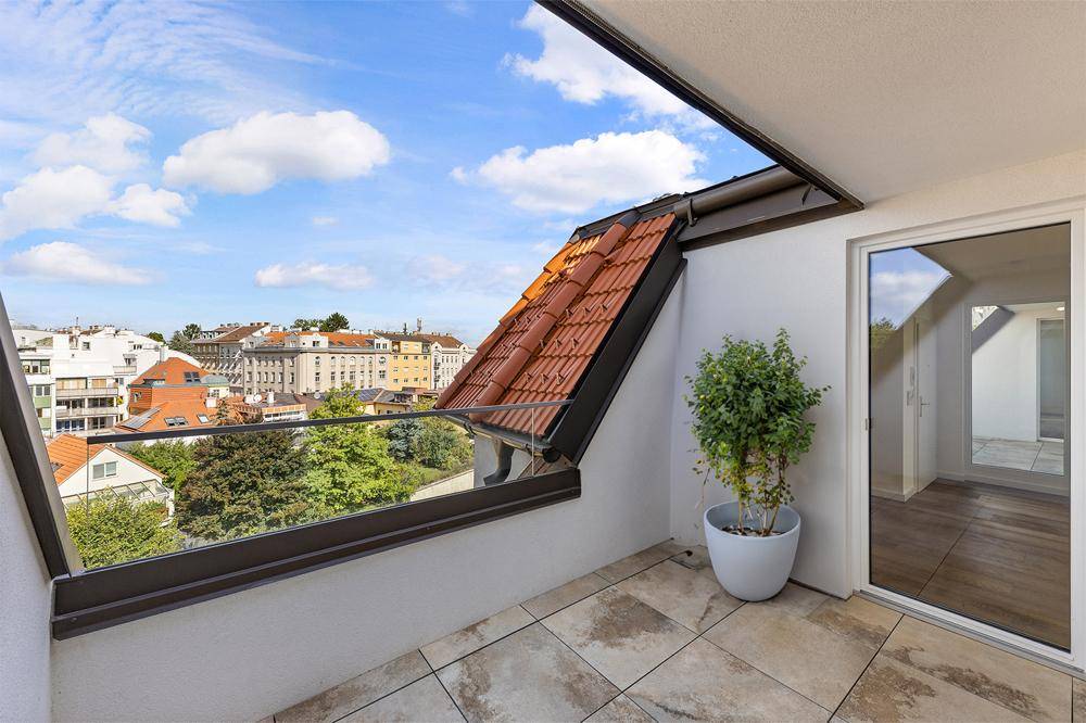 Heller Balkon mit Fliesenboden und Glasgeländer, bietet einen weiten Blick über die Stadt.