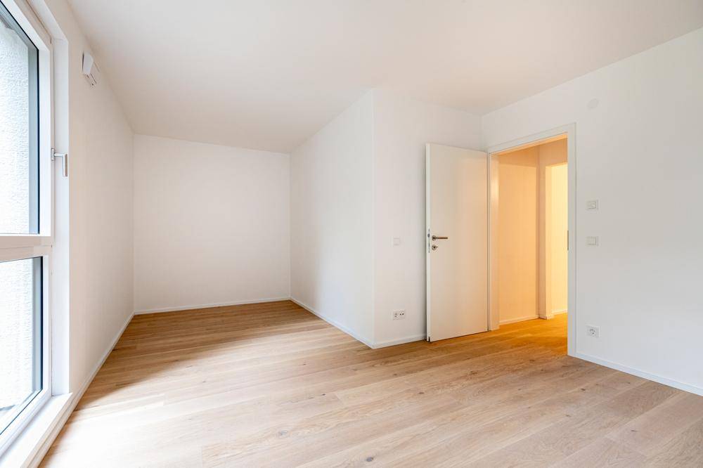 Helles, leeres Zimmer mit Eichenparkett und Fenster, bereit zur individuellen Gestaltung.