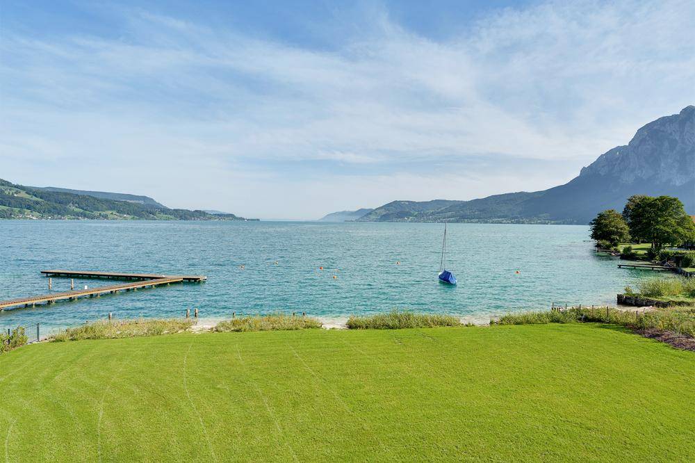 Weitläufiger Gartenbereich mit direktem Zugang zum See und malerischem Bergblick.