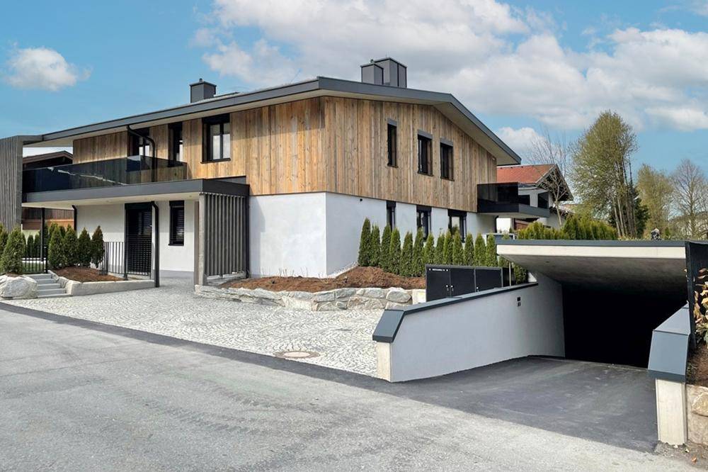 Moderne Villa mit Zufahrt zur Tiefgarage und gepflegter Außenanlage.