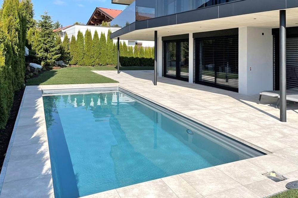 Außenbereich mit großem Pool, gepflegtem Rasen und sonniger Terrasse.