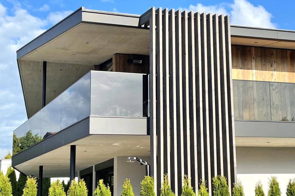 Detailansicht der modernen Fassade mit Holzverkleidung und Glasbalkon.