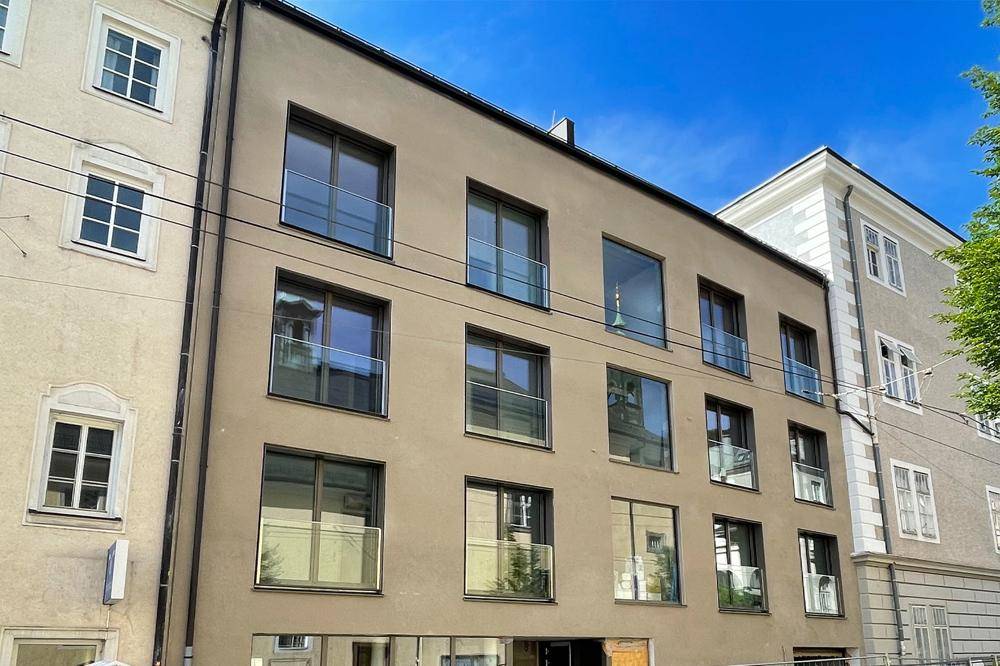 Ansicht der modernen Gebäudefassade mit zahlreichen Fenstern und Glasbalkonen unter klarem Himmel.