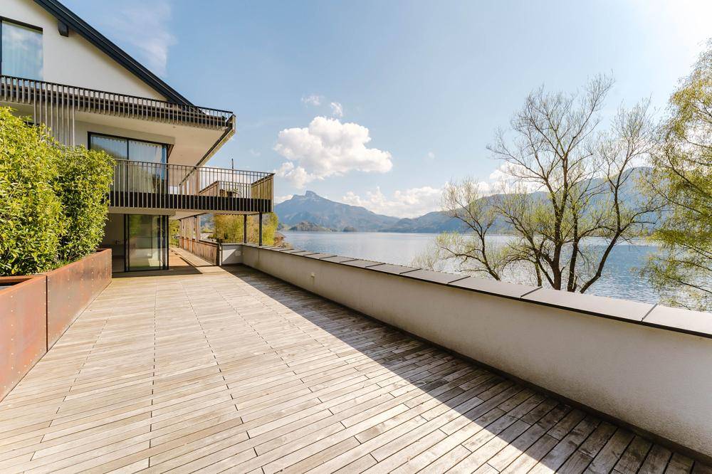 Geräumige Holzterrasse mit weitem Blick auf den See und die umliegende Berglandschaft.