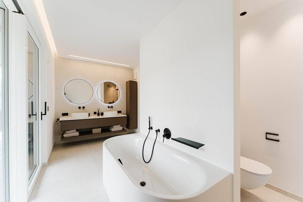 Modernes Badezimmer mit freistehender Badewanne, Doppelwaschbecken und minimalistischem Design.
