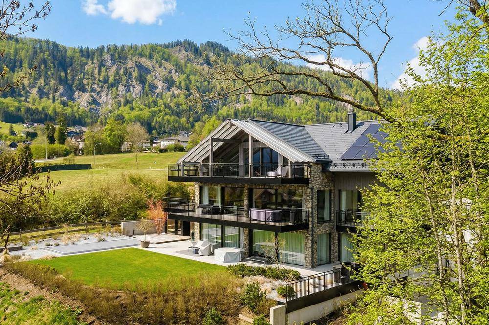 Exklusives Anwesen mit moderner Architektur, Glasfassade, mehreren Balkonen und kleinem Poolbereich.