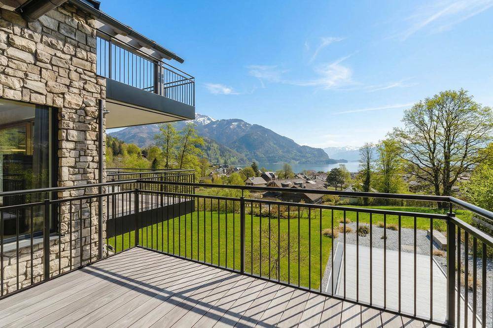 Balkon mit Steinmauer, Holzdeck und weitem Blick auf die umliegende Natur und den See.
