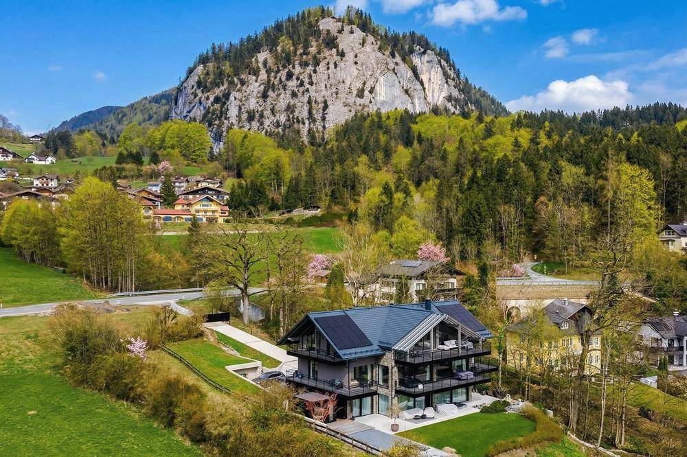 Moderne Architektur des Anwesens mit Solaranlage auf dem Dach und beeindruckender Bergkulisse.