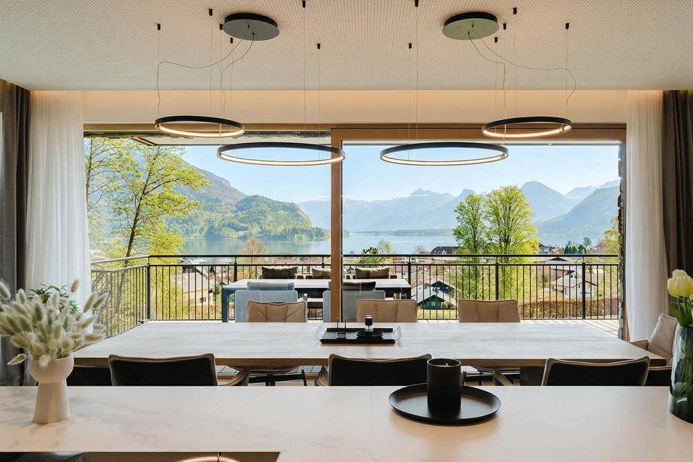 Eleganter Essbereich mit modernem Design, großen Fenstern und herrlichem Blick auf See und Berge.
