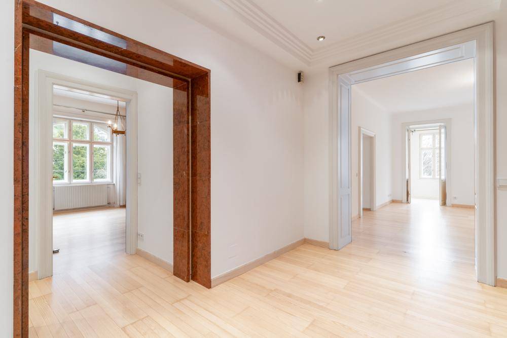 Heller Flur mit Holzboden und eleganten Türrahmen, verbindet mehrere Räume.