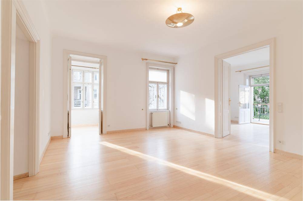 Lichtdurchfluteter Raum mit Parkettboden, hohen Fenstern und klassischer Architektur.