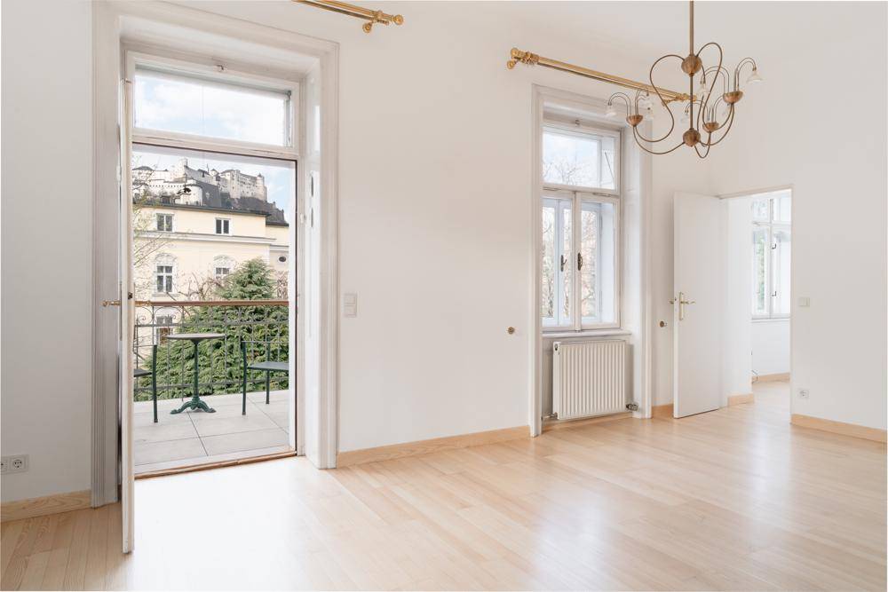 Geräumiges Zimmer mit Balkonzugang, Parkettboden und Blick auf die Festung Hohensalzburg.