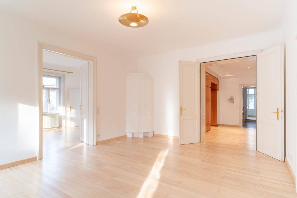 Helles, leeres Zimmer mit Holzboden und hohen Türen, bereit zur individuellen Gestaltung.