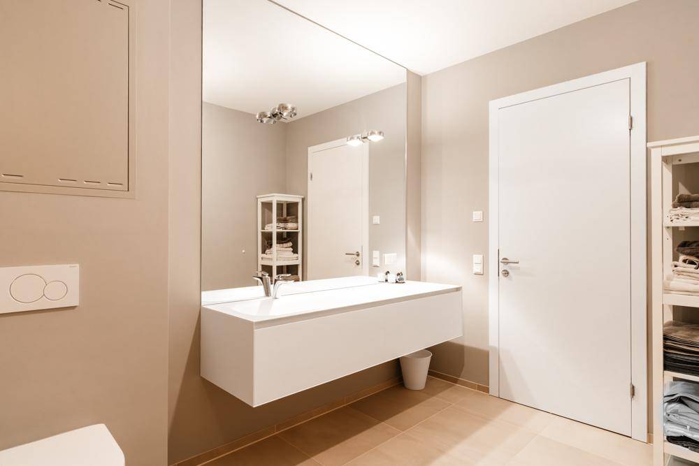 Modernes Badezimmer mit schwebendem Waschtisch, großem Spiegel und wandhängendem WC.