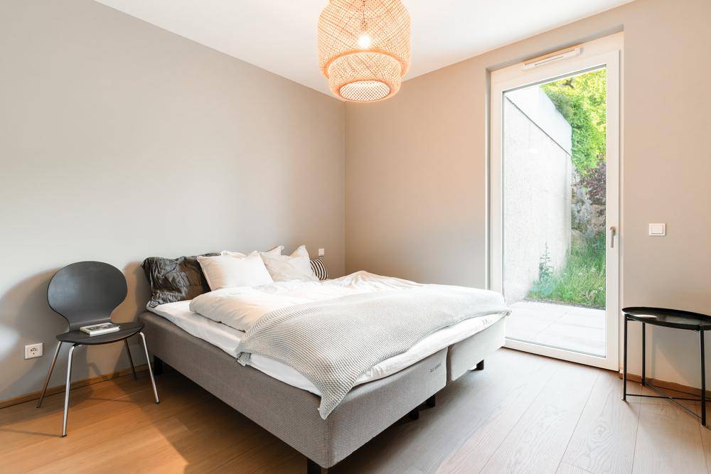 Gemütliches Schlafzimmer mit Doppelbett, Holzboden und Zugang zu einem kleinen Außenbereich.