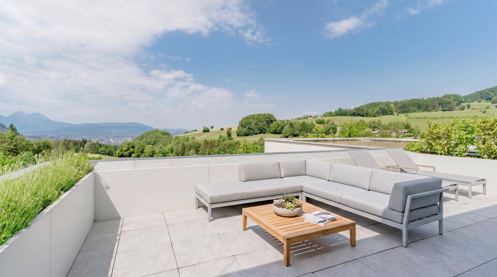 Geräumige Dachterrasse mit modernen Loungemöbeln und weitem Blick über die grüne Landschaft.