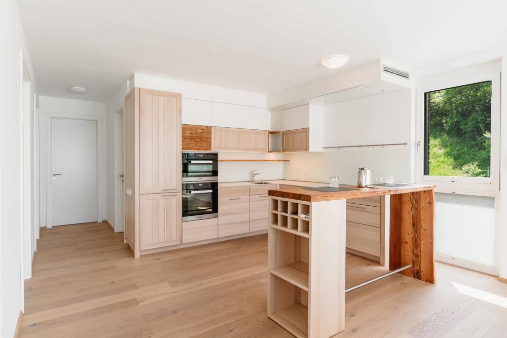 Moderne Einbauküche mit hellen Holzfronten, integrierten Geräten und einer praktischen Kücheninsel.