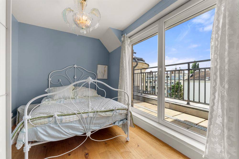 Gemütliches Schlafzimmer mit Holzboden, blauen Wänden und direktem Zugang zum Balkon.