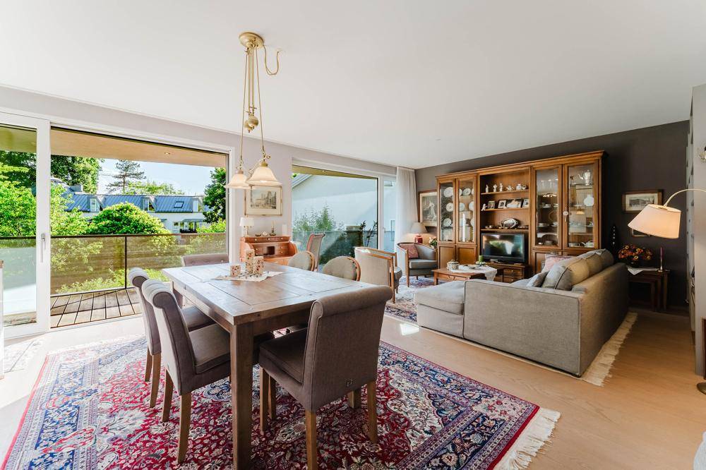 Geräumiger Wohn-Essbereich mit traditionellen Möbeln, Teppich und Zugang zum Balkon.