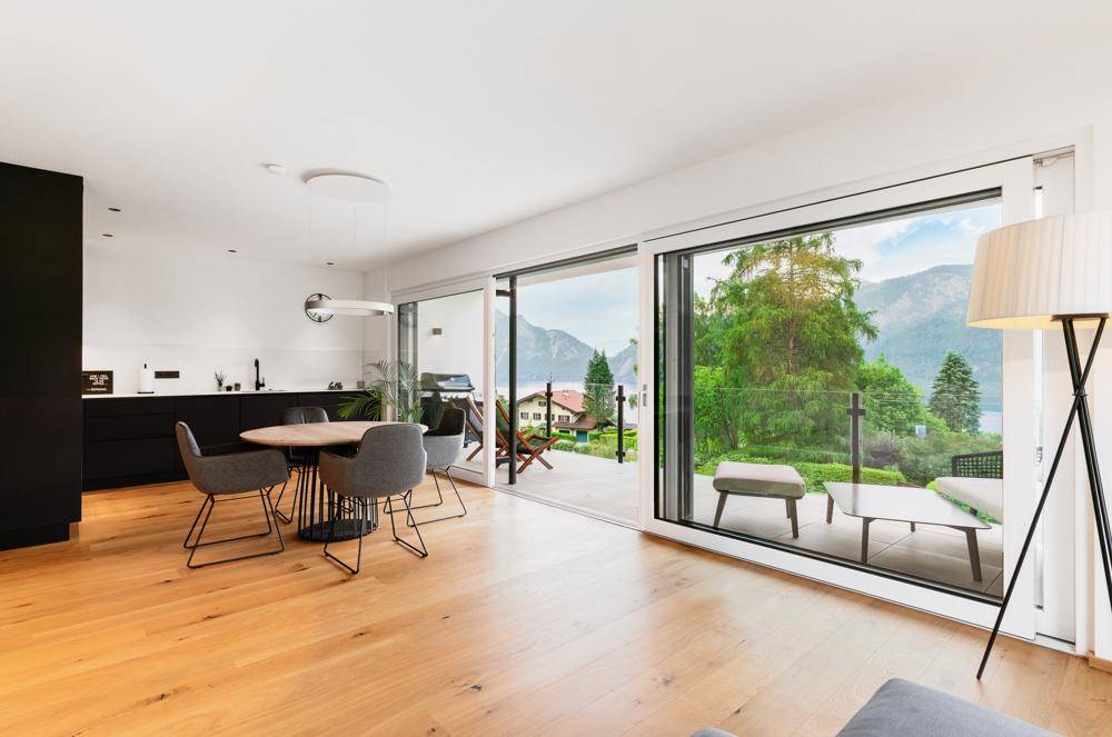 Heller Wohn-Essbereich mit Holzboden, modernem Esstisch und Zugang zur Terrasse mit Seeblick.