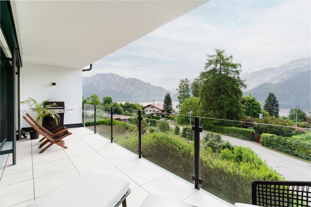 Geräumige Terrasse mit modernen Lounge-Möbeln, Grill und atemberaubendem Blick auf den See und die Berge.