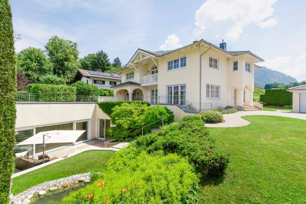 Elegantes Haus mit weitläufigem Garten, Teich und einer unteren Terrasse mit Bergblick.