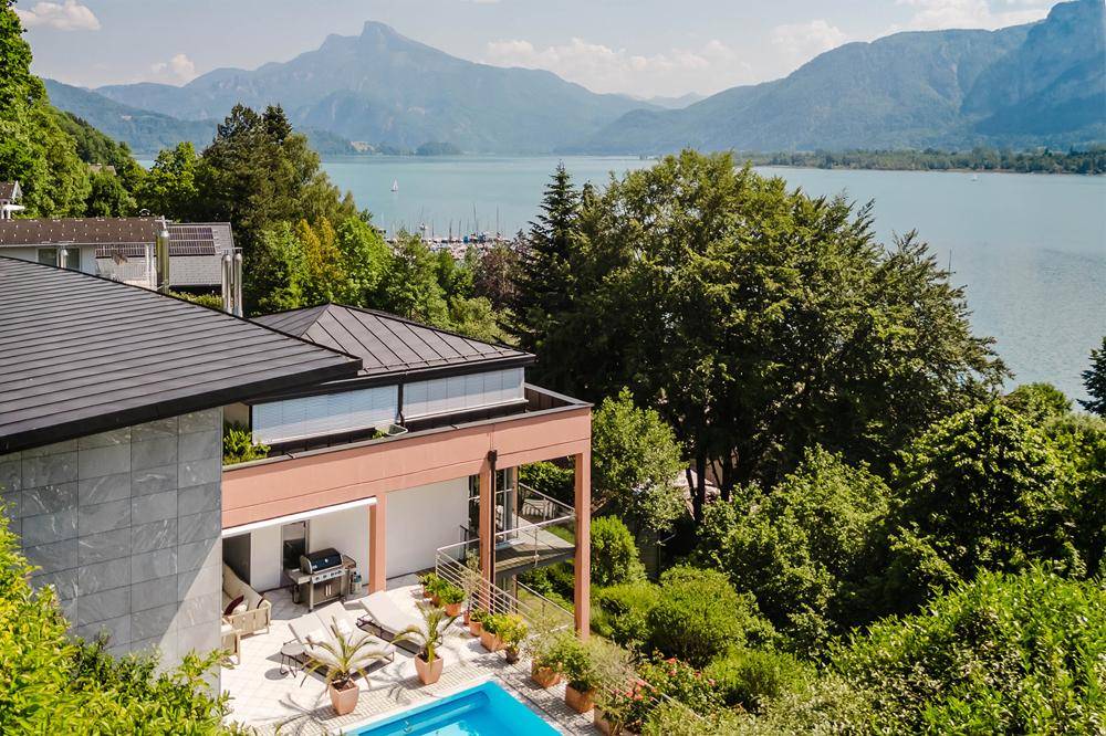Exklusives Anwesen mit Pool und Terrasse, umgeben von üppiger Natur mit Blick auf den See und die Berge.