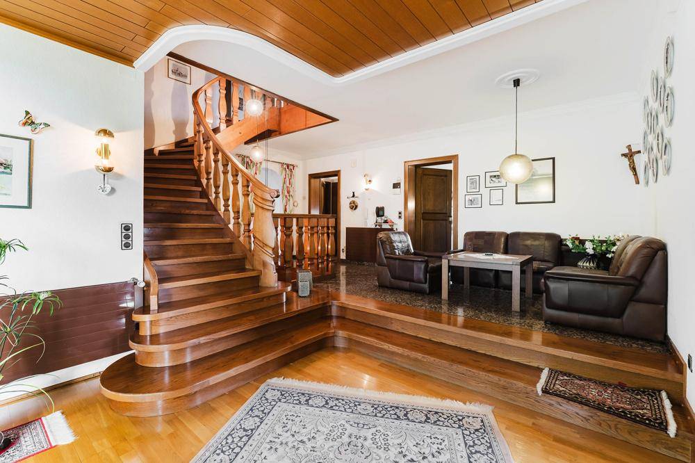 Geräumiger Eingangsbereich mit eleganter Holztreppe und traditioneller Einrichtung, die zu weiteren Räumen führt.