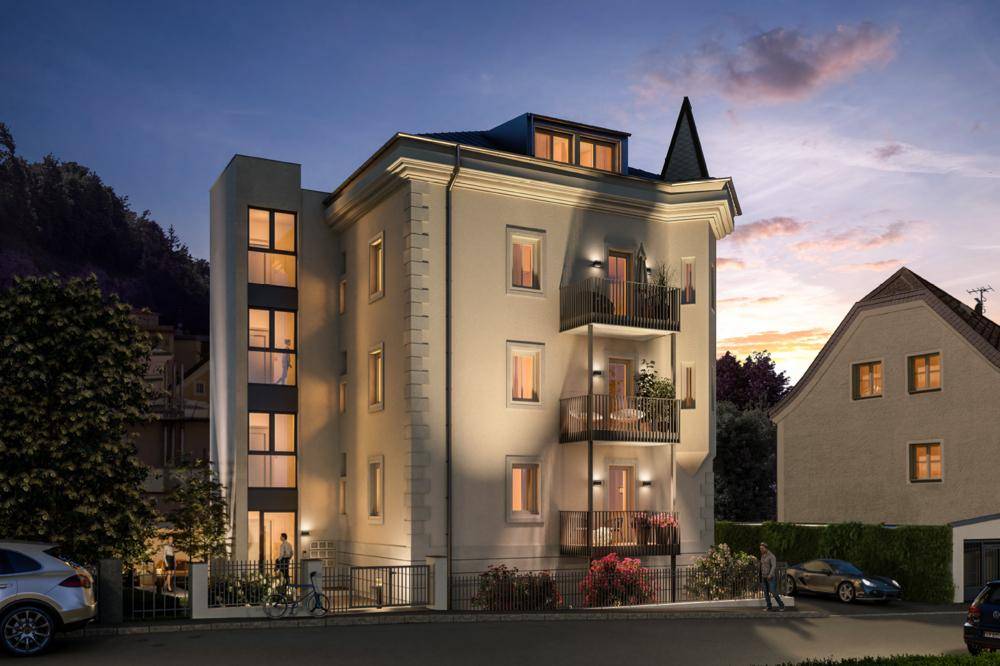 Abendliche Darstellung des Wohnhauses mit beleuchteten Balkonen und moderner Architektur bei Sonnenuntergang.
