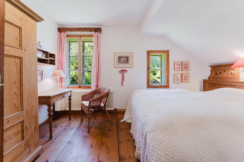 Helles Schlafzimmer mit Holzboden, Dachschräge und Blick ins Grüne.