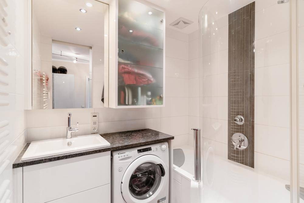 Modernes Badezimmer mit Dusche, Waschbecken und integrierter Waschmaschine.